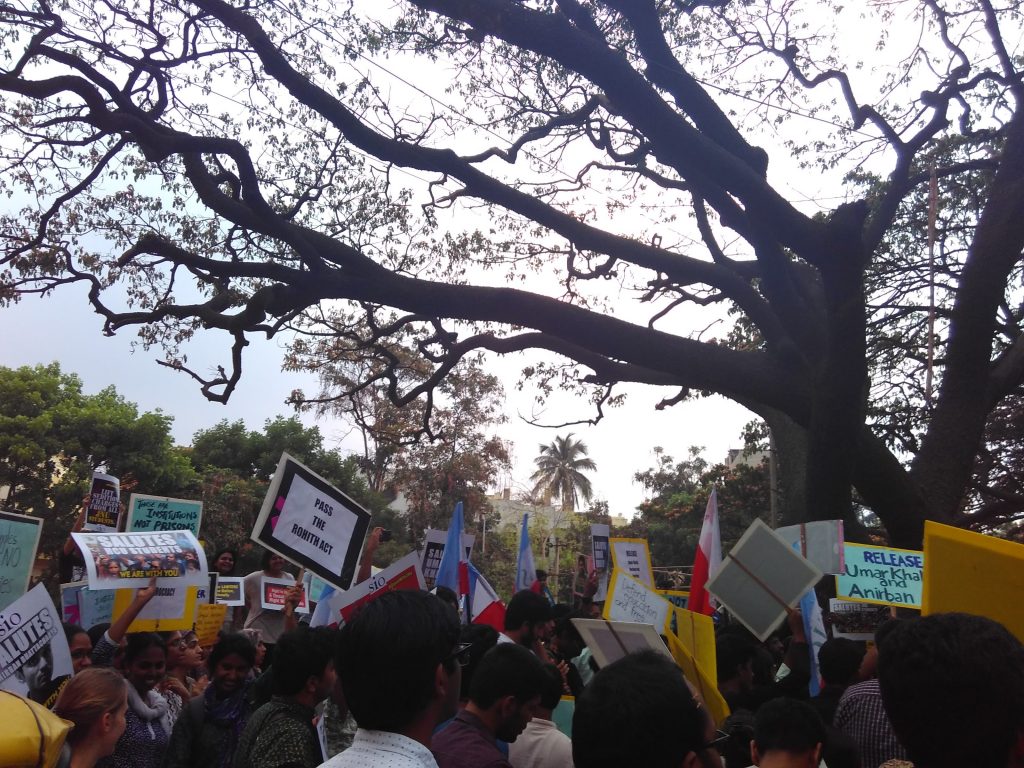 Protest with lots of people holding placards saying things like 'Pass the Rohith Act'