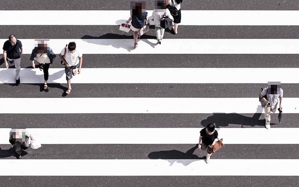 An image of a zebra crossing with several people walking across. Five of the people have been pixelated.