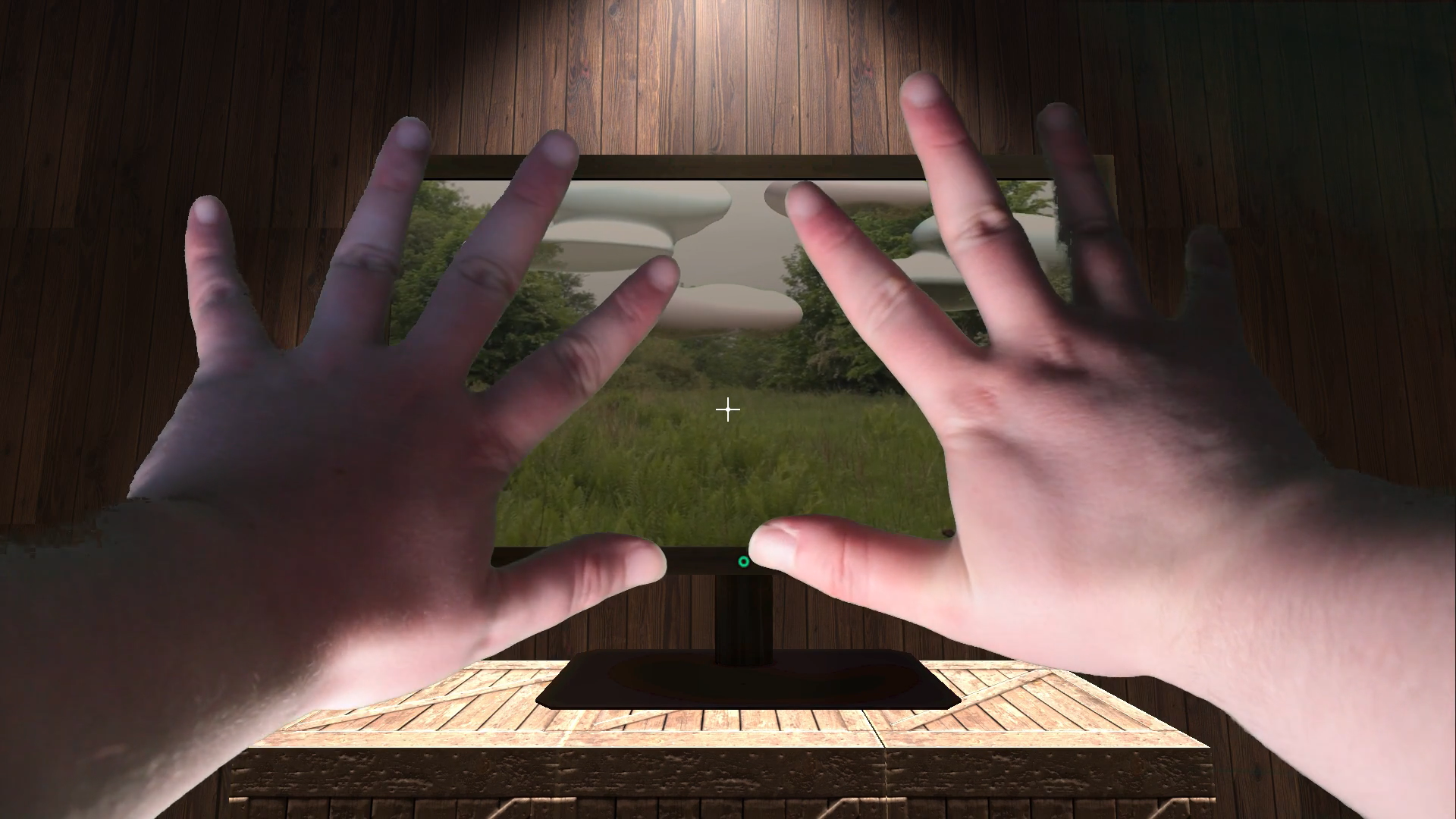 A pair of hands stretch out towards a computer-generated image of a wooden desk with a computer on it. On the screen is a picture of a park with green grass and a grey sky
