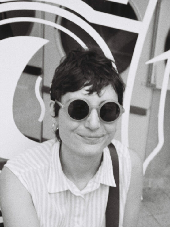 black and white image of Harriet, with short dark hair, sunglasses and a sleeveless shirt