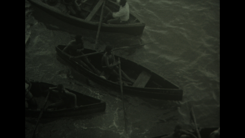 still from old film footage of people in the Caribbean in row boats