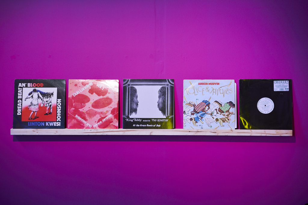 A shelf of five vinyl record covers on a purple wall