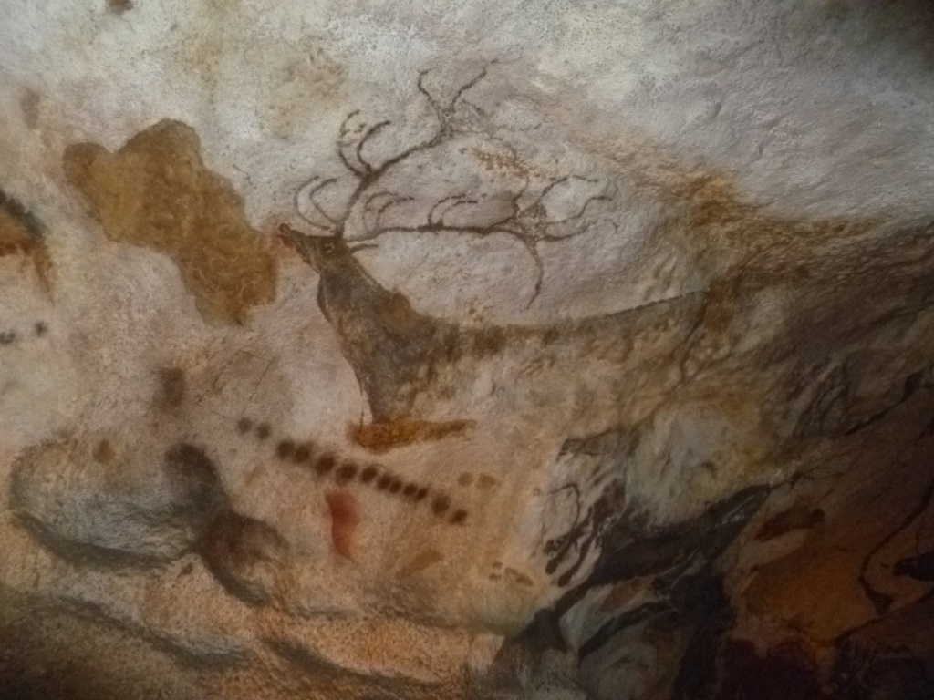 A wall of cave paintings at Lascaux, with a stag and antlers centrally, underlined by abstract marks
