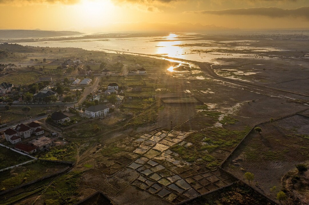 a flooded plain covering fields and encroaching on houses during a sunrise
