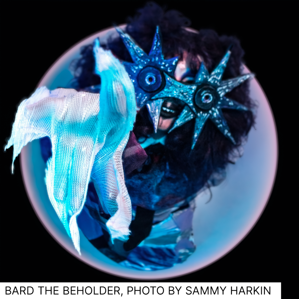 A fisheye lens photo of a performer in costume, with star shaped goggles and big hair