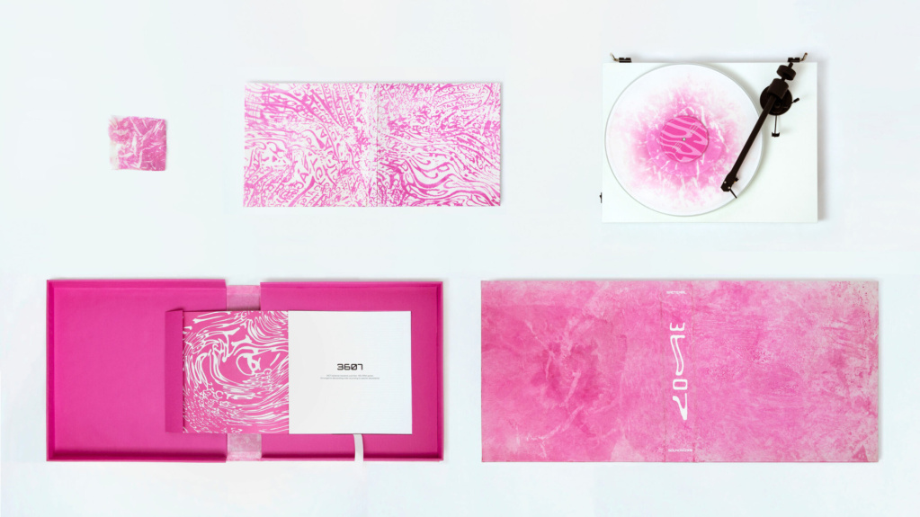 A layout of the elements of 3607 Bacterial soundscape on a table, a vinyl record and the case it is kept in and the book documenting the project all in bright pink