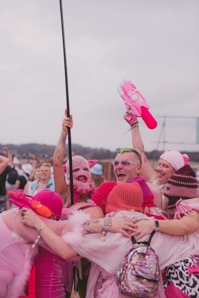 a group of cute cartel performers in a celebratory huddle at a festival