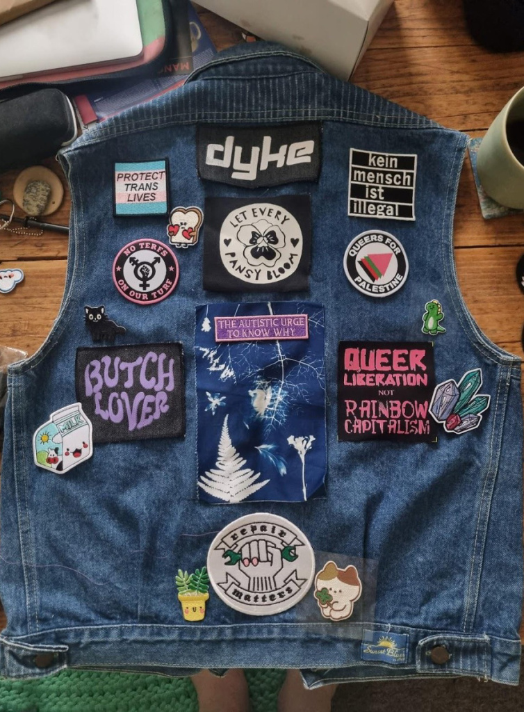 A jacket covered with patches for queer and community collective resistance